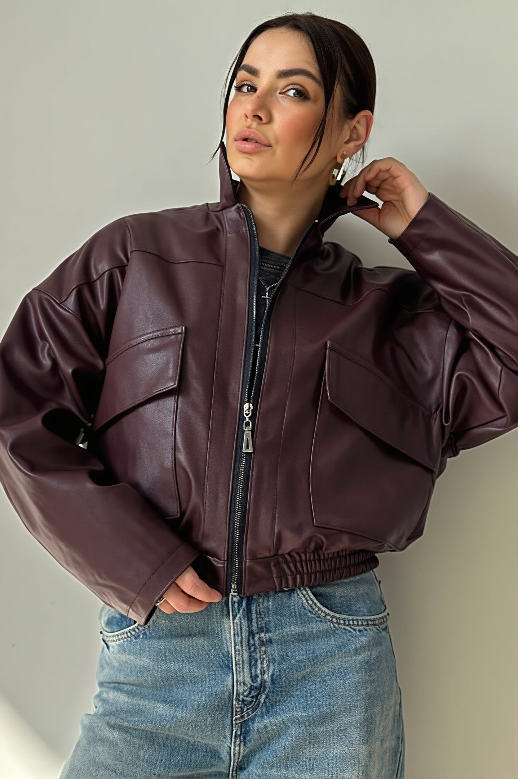 Side view of a faux leather bomber jacket with ribbed cuffs