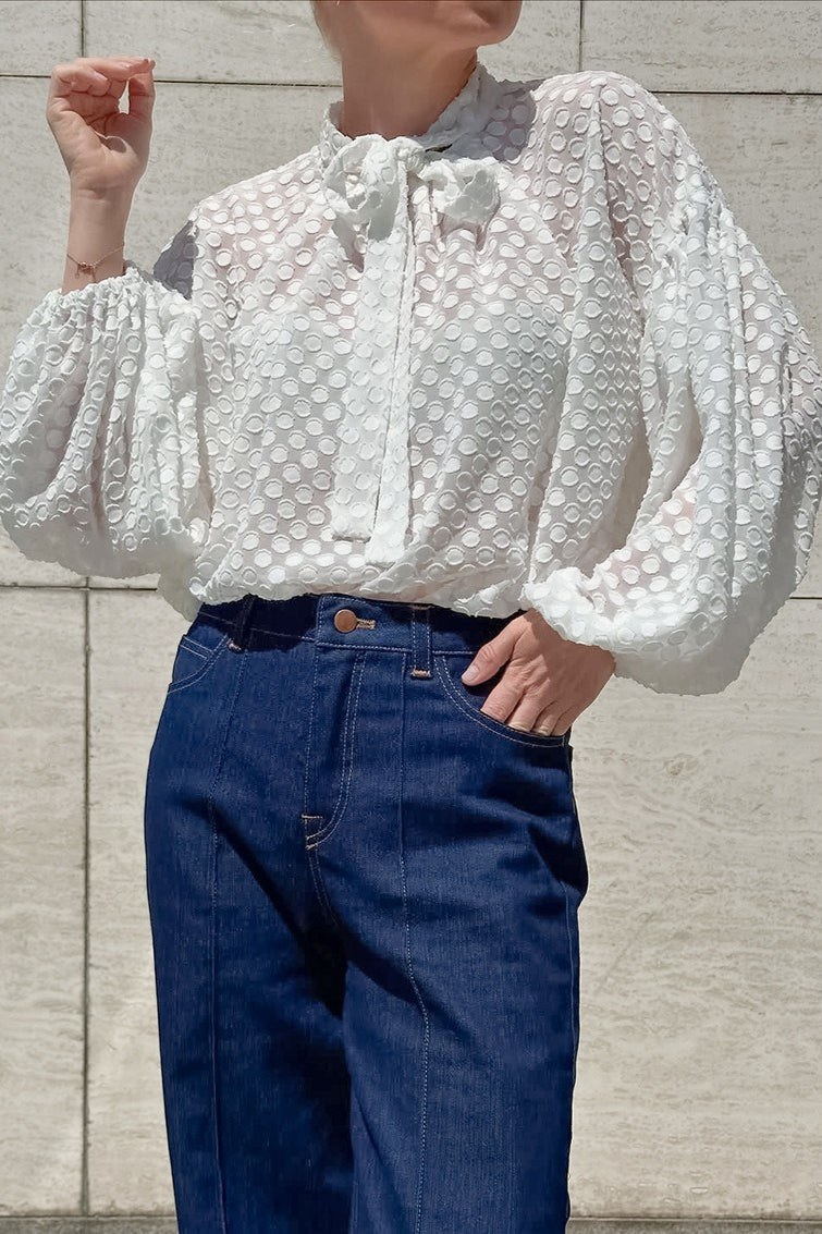 White textured tie neck blouse with balloon sleeves shown on a model