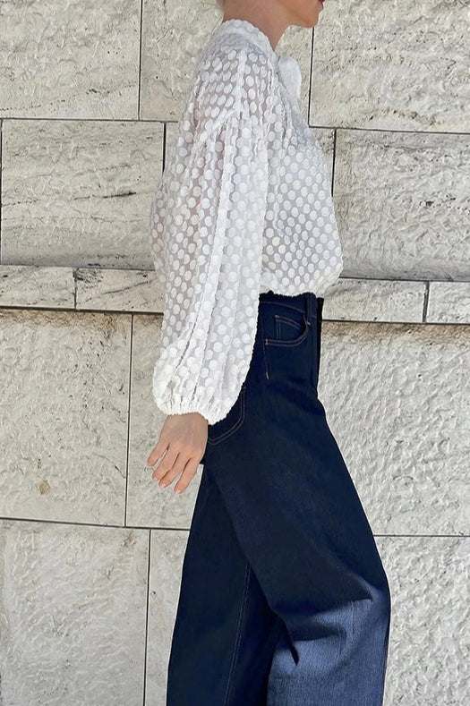 Close-up of the textured white fabric and tie neckline on the blouse