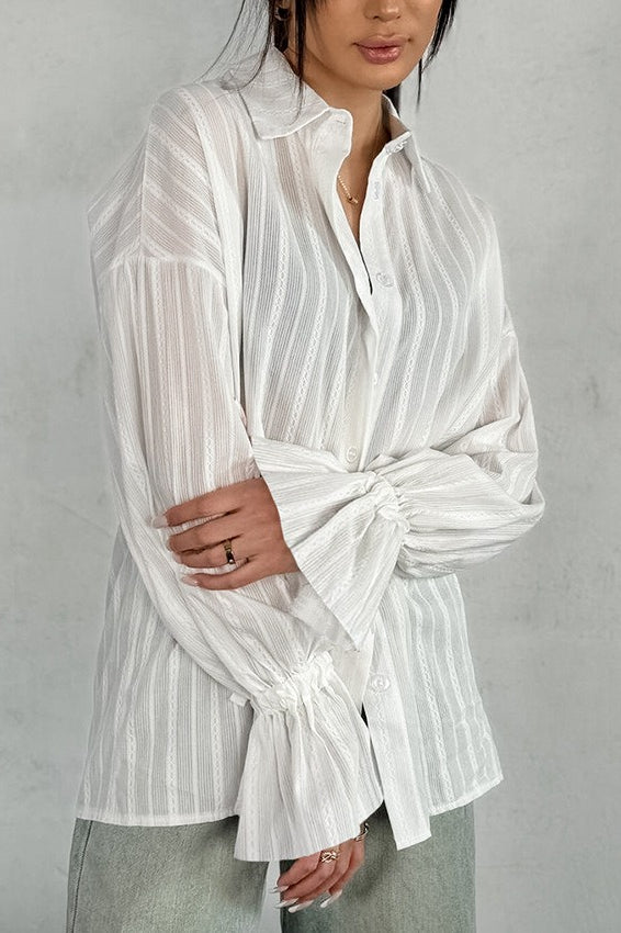 Close-up of the shirt's sheer striped fabric and ruffle cuff detail