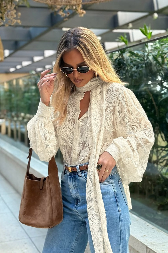 Front view of a women's beige lace tie-neck blouse