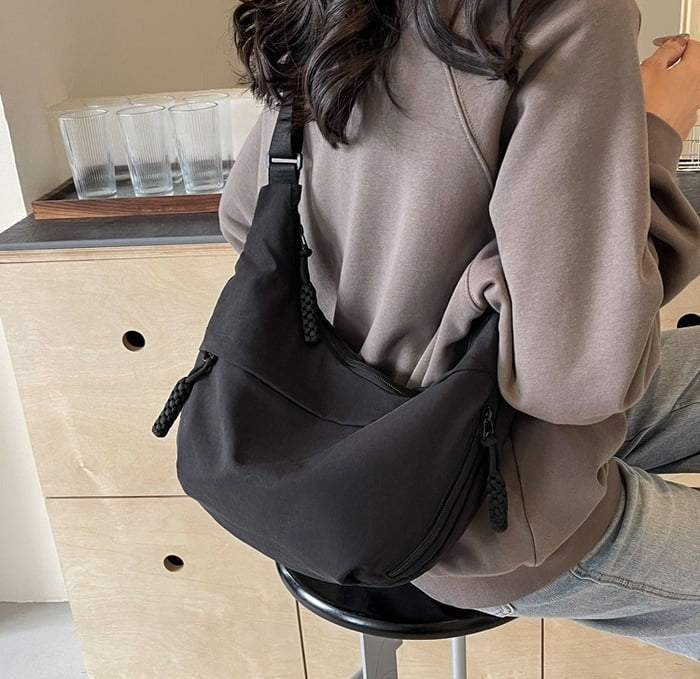 Side view of women's nylon crossbody bag with multiple zip compartments