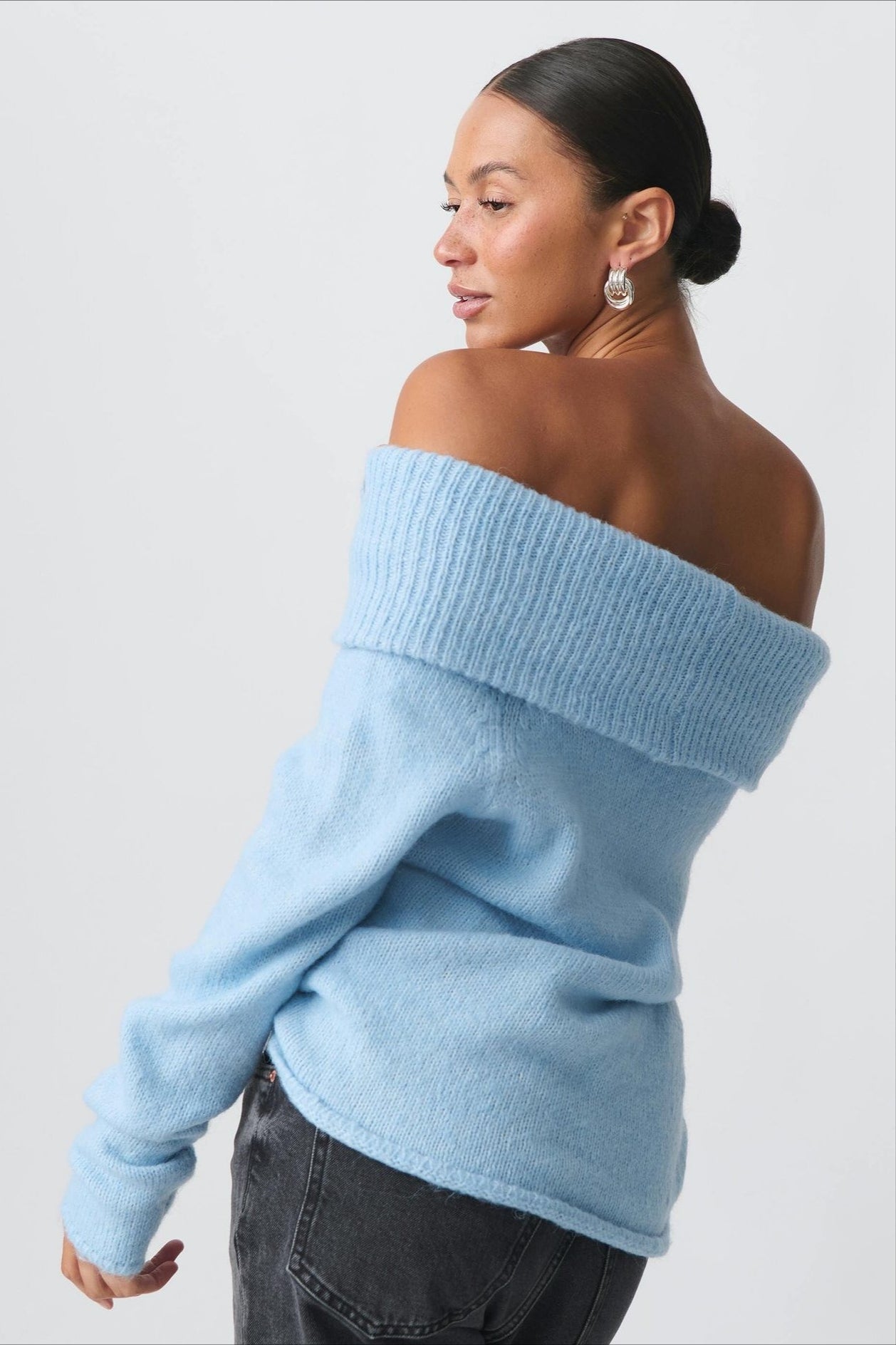 Model wearing the off-shoulder fitted sweater in a polished outfit