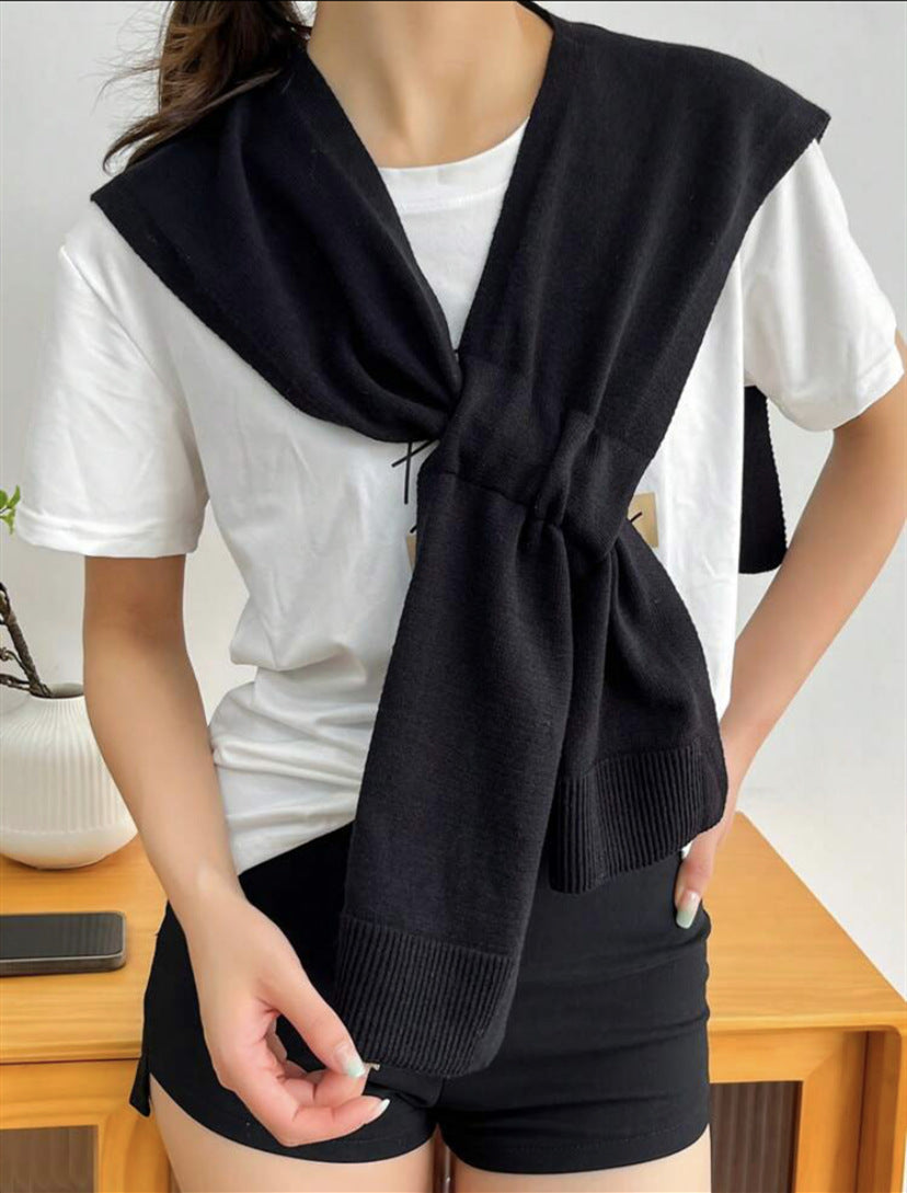 Close-up of a women's knit scarf showing its textured weave and knot detail.