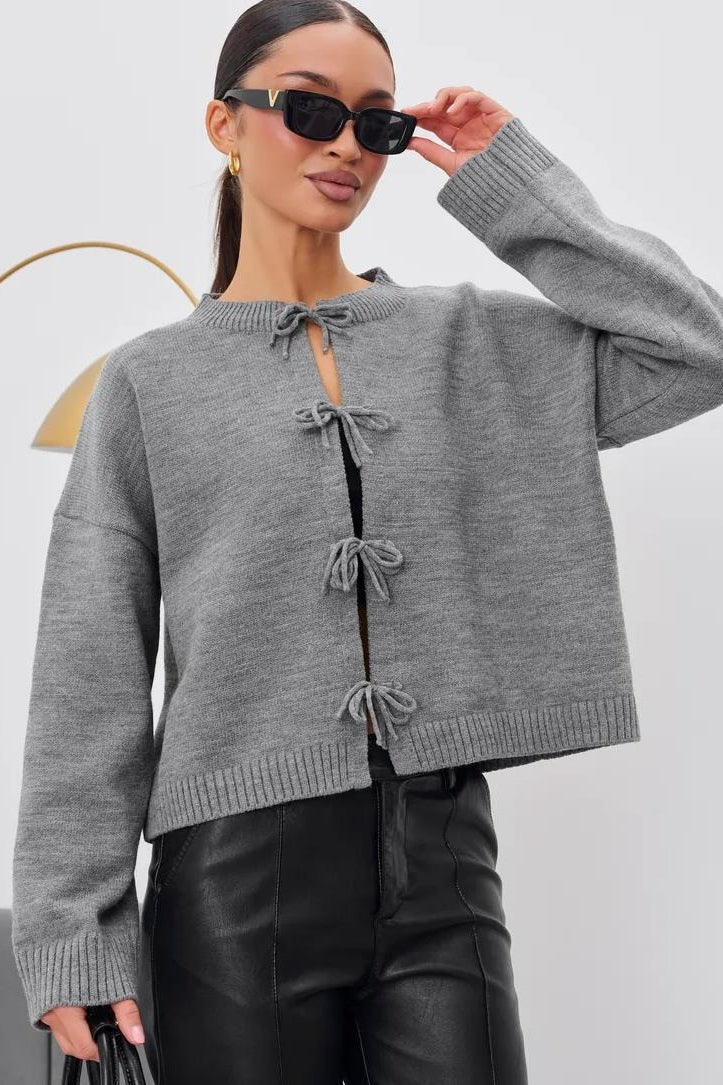 Close-up of the crew neckline and tie-front detail on a knit cardigan