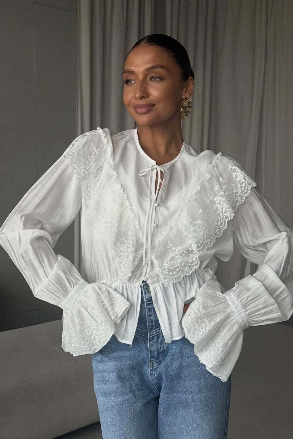 Women's blouse featuring a delicate lace yoke and ruffle hem