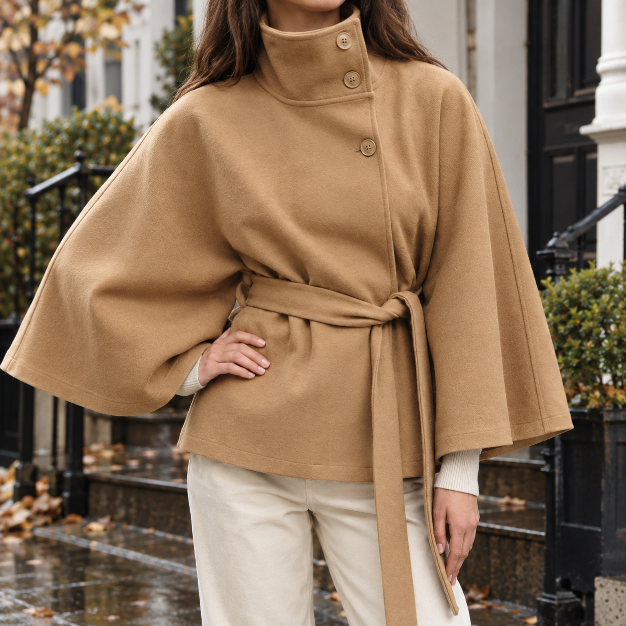 Cape jacket with a stand collar and tie belt shown from the front
