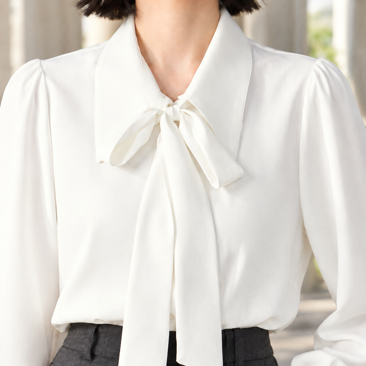 Close-up of the women's blouse showing its tie neck and pointed collar