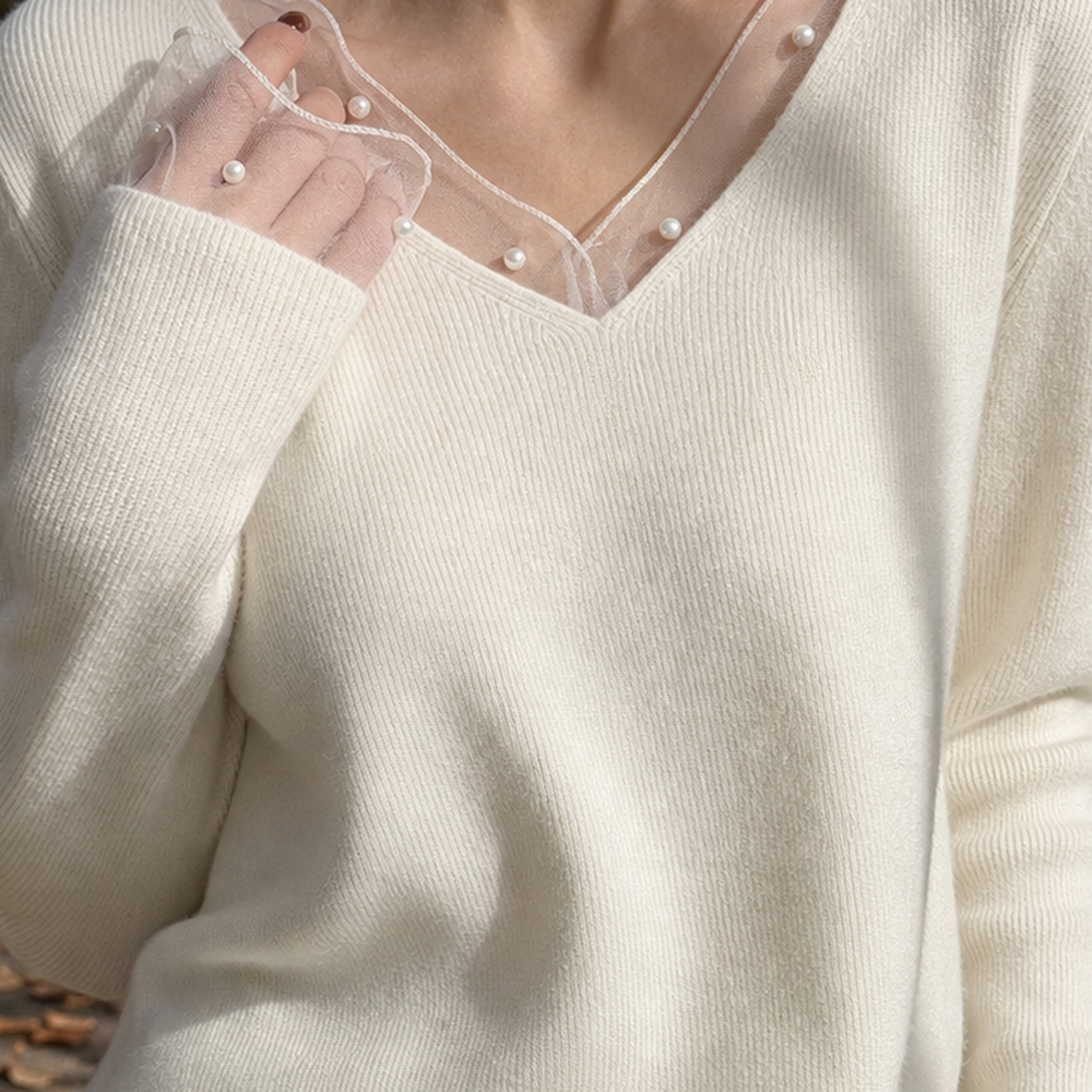 Close-up of pearl trim detailing on a women's ribbed V-neck sweater