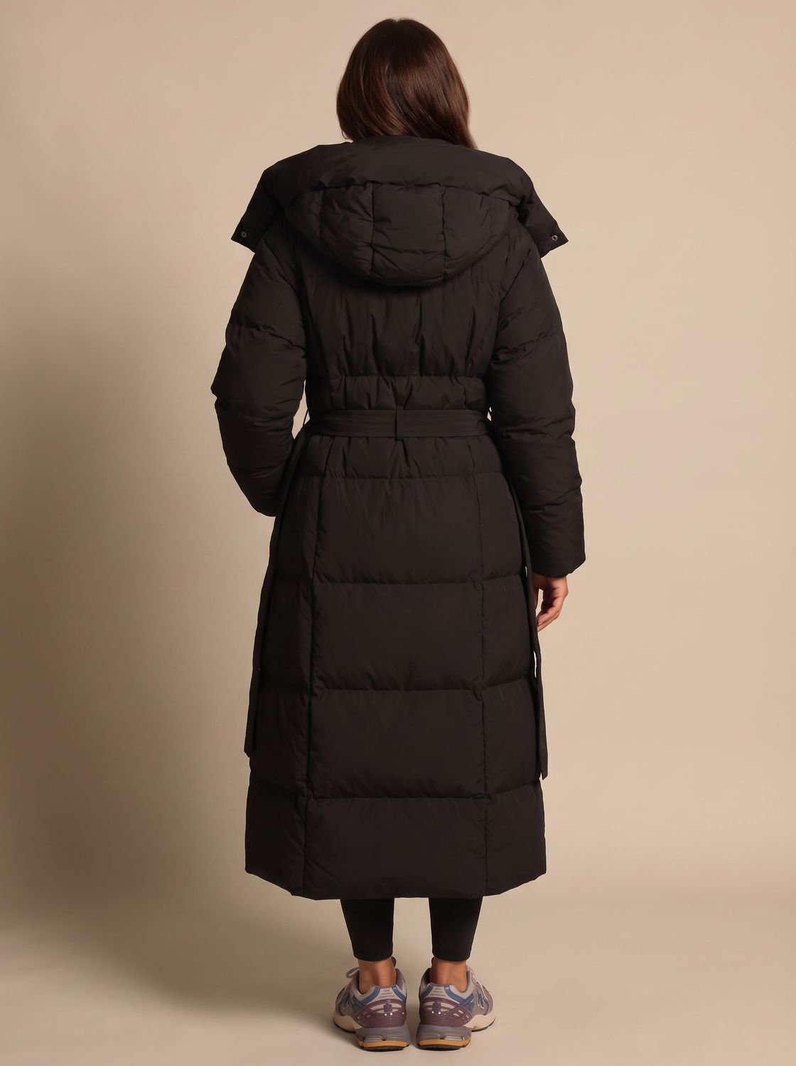Side view of a belted hooded puffer coat with a longline silhouette