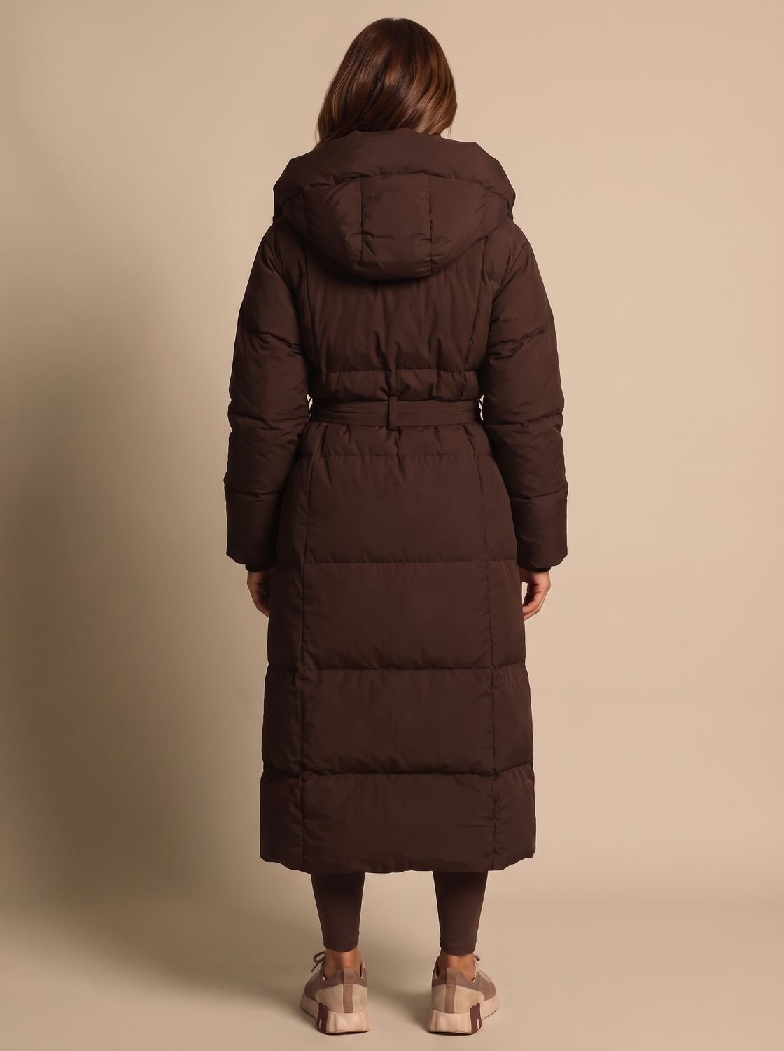 Back view of a long hooded puffer coat with a belted waist